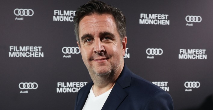 Bastian Pastewka bei vor einer Fotoleinwand.