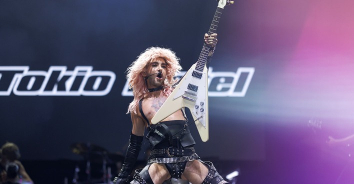 Bill von Tokio Hotel mit einem engen Lederoutfit und einer Gitarre auf der Bühne.