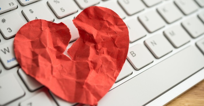 Gebrochenes Papier-Herz auf einer Computertastatur
