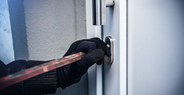 Einbrecher mit schwarzen Handschuhen bricht Tür auf