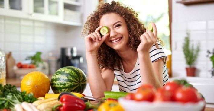 Frau mit lockigem Haar beim kochen von veganem Essen