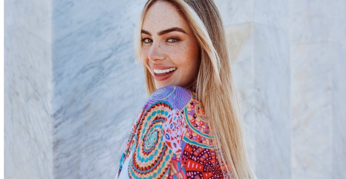 Blonde Frau im sommerlichem bunten Kleid lächelt