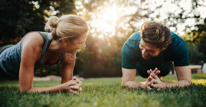 Eine Frau und ein Mann beim Sport im Park, sie führen eine Plank-Übung aus