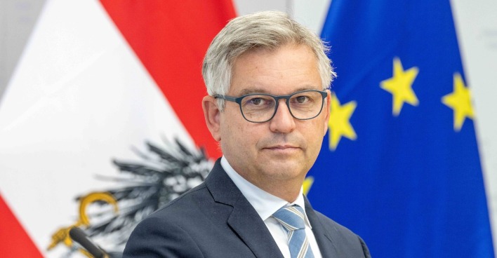 Magnus Brunner, EU-Kommissar in spe, vor der österreichischen und der EU-Flagge im Porträt