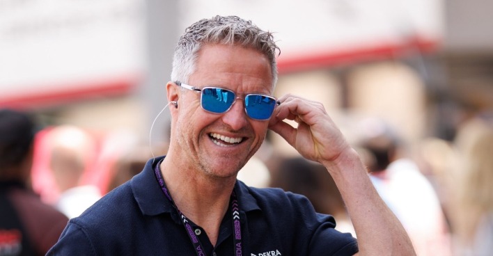 Ralf Schumacher bereit lachend, greift an seine Sonnenbrille