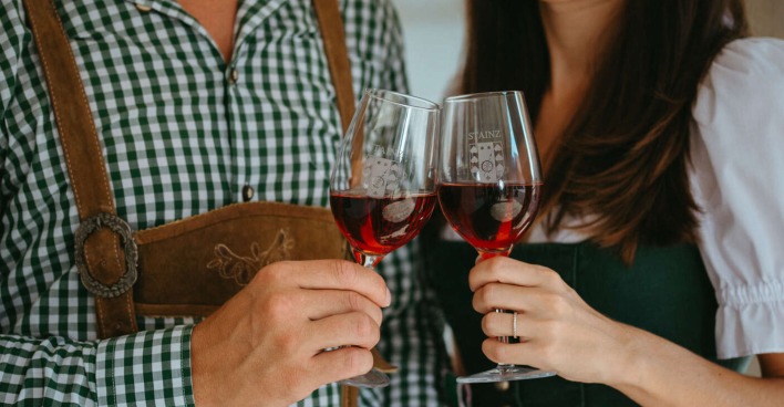 Mann und Frau in Tracht stoßen mit einem Wein an