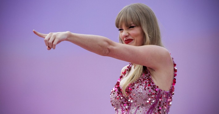 Talyor Swift, Blond in glitzerndem Oberteil auf der Bühne, sie zeigt in die Menge