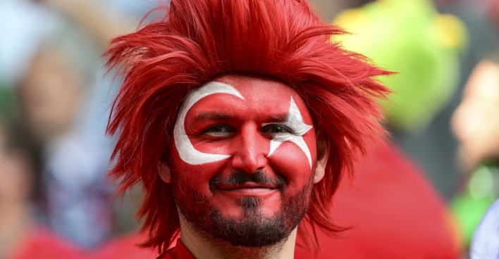 Fußballfan mit roter Perücke und den türkischen Landesfarben im Gesicht