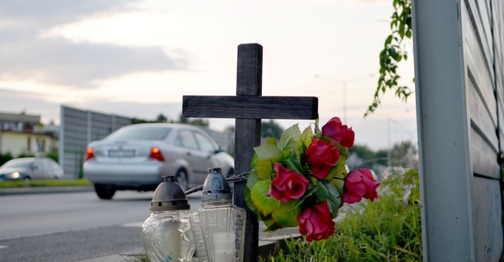 Ein Kreuz und Kerzen am Fahrbahnrand.
