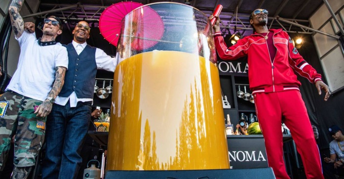 Der Rapper Snoop Dogg auf einer Bühne neben einem 500 Liter-Cocktail in einem überdimensional großen Glas samt Strohhalm