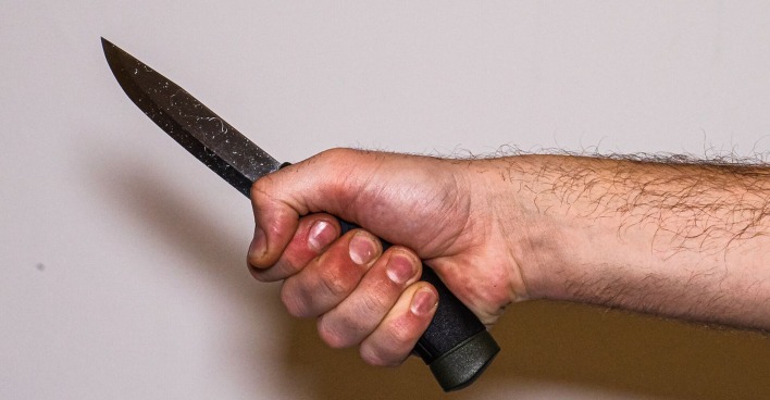 der Arm eines Mannes mit einem Küchenmesser in der Hand