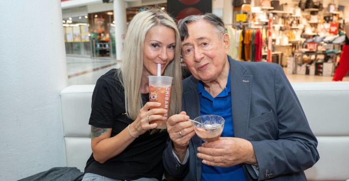 Eine Frau und ein Mann sitzen nebeneinander und trinken Kaffee