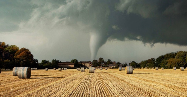 Ein Tornado fegt über ein Feld mit Heuballen.