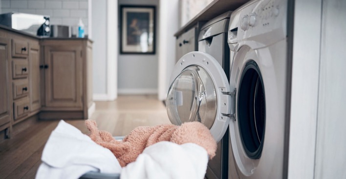 Wäschekorb steht vor einer Waschmaschine | Credit: iStock.com/PeopleImages