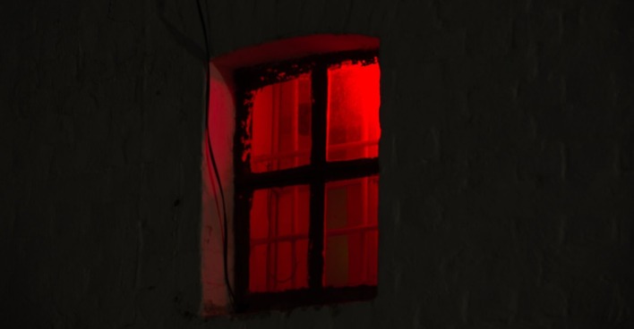 Ein Fenster in der Nacht, in dem ein rotes Licht scheint.