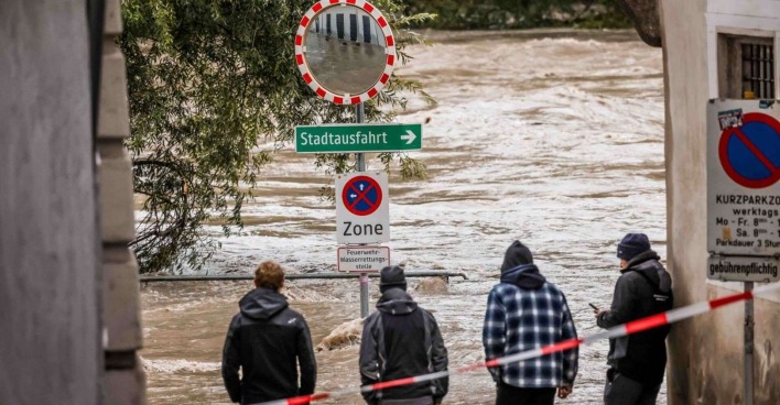 Vier Männer blicken auf eine überschwemmte Straße.
