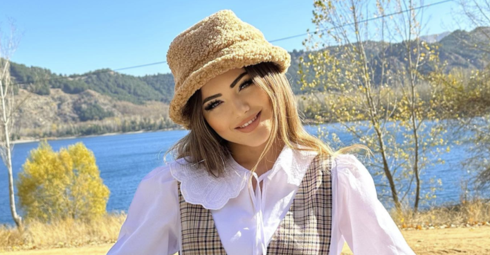 Influencerin Kübra Aykut mit einem Hut lächelt in die Kamera.