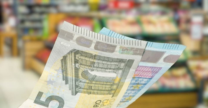 25 Euro in Scheinen vor dem Hintergrund eines Supermarkts.