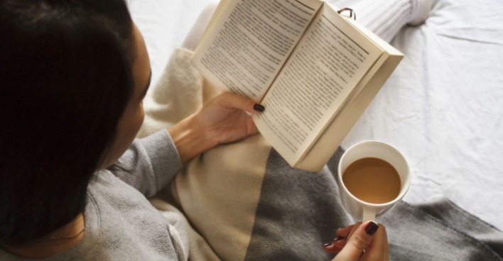 Frau sitzt mit Buch auf der Couch | Credit: iStock.com/Mima88