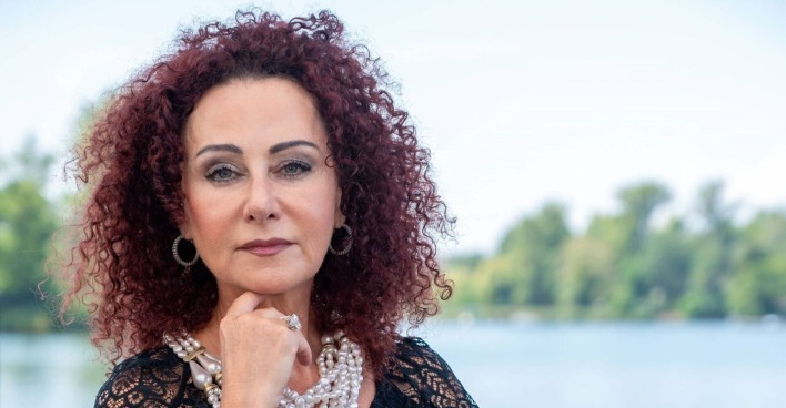 Mausi Lugner mit Perlenketten blickt ernst in die Kamera.