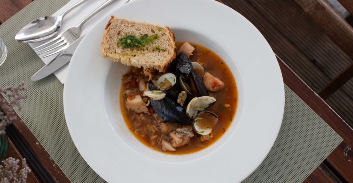 Die Fischsuppe mit Muscheln, Fischstücken und Garnele wird im Panigl mit einem Stück getoastetem Weißbrot serviert.