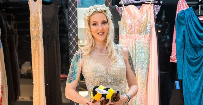 Simone Lugner in einem Kleid mit einer Stoff-Biene in den Händen.