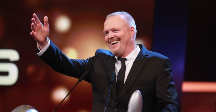 Stefan Raab spricht auf der Bühne in ein Mikrophon.
