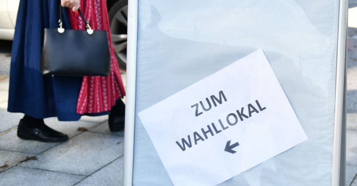 Eine Frau im Dirndl geht ins Wahllokal.