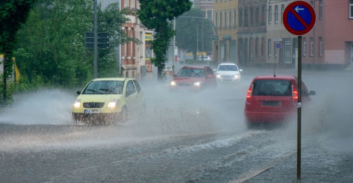 Starker Regen auf den Straßen, Autos fahren durch zentimeterhohes Wasser