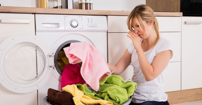 Frau sortiert die Wäsche vor der Waschmaschine | Credit: iStock.com/AndreyPopov