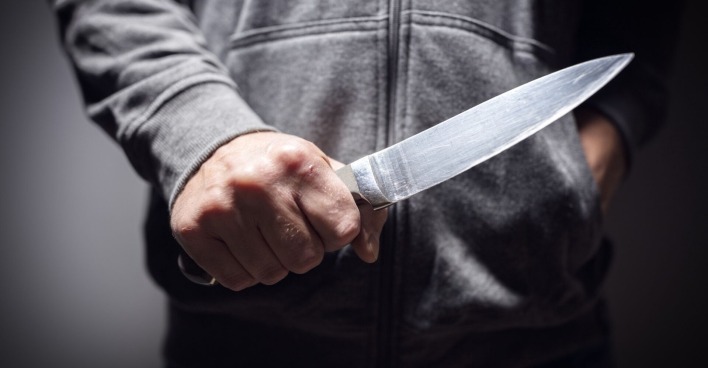 Ein junger Mann hält ein Messer in der Hand.