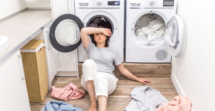 Frau sitzt frustriert vor Waschmaschine | Credit: iStock.com/Mariakray