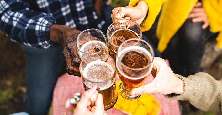 Vier Menschen halten ein Glas in der Hand und stoßen an