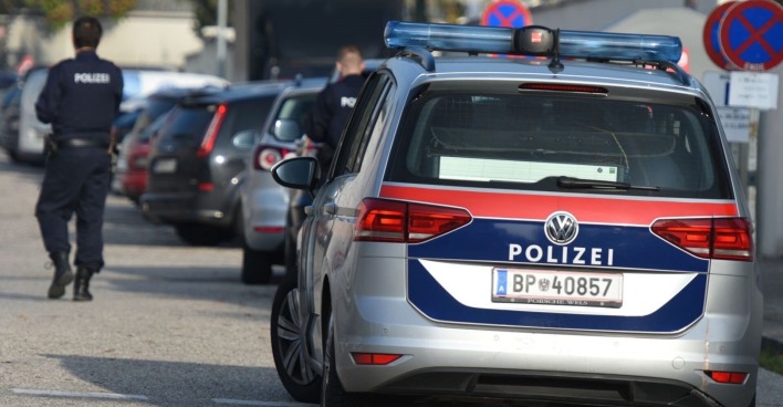 Ein Polizist und ein Polizeiauto auf einer Straße.