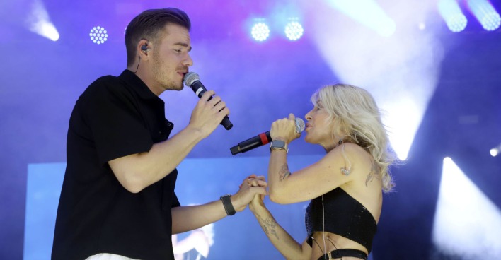 Ein Mann und eine Frau singen und halten sich die Hände auf der Bühne