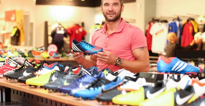 Thomas Winklhofer hält im Sportgeschäft einen Fußballschuh hoch.