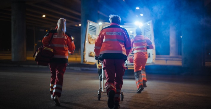 Drei Rettungskräfte eilen zum Notarztwagen.