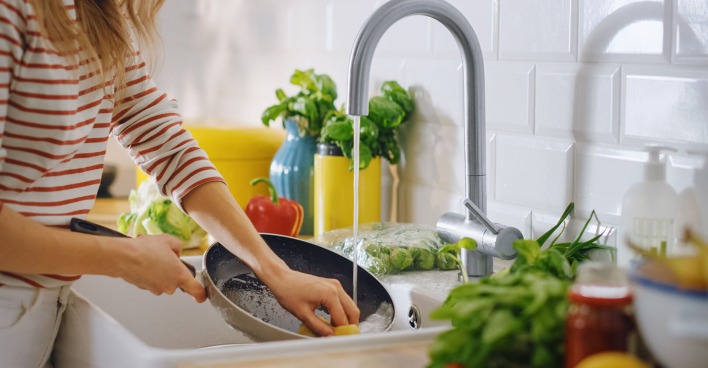 Frau reinigt Pfanne | Credit: iStock.com/gorodenkoff