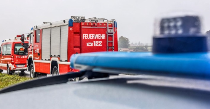 Zwei Feuerwehrautos und ein Polizeiwagen an einen Unfallort.