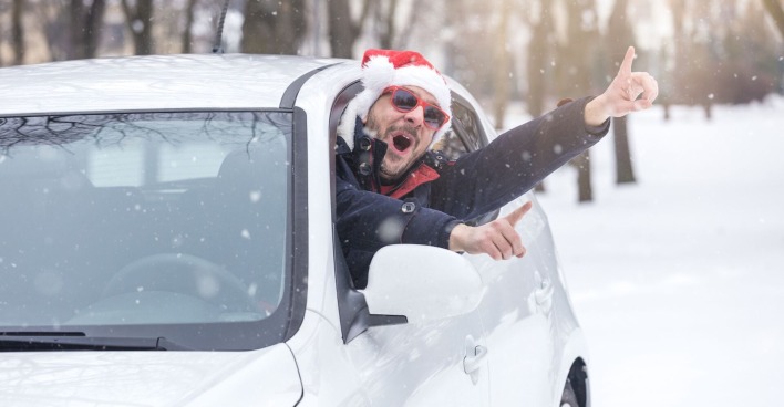 Ein Mann mit Weihnachtsmütze winkt aus dem Auto.