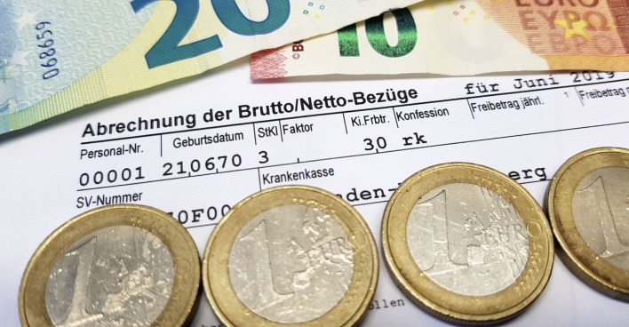 Lohnabrechnung und Euro-Münzen sowie -Scheine.