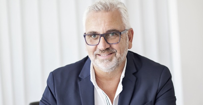 Mann mit weißem Haar und dunkelblauen Sakko