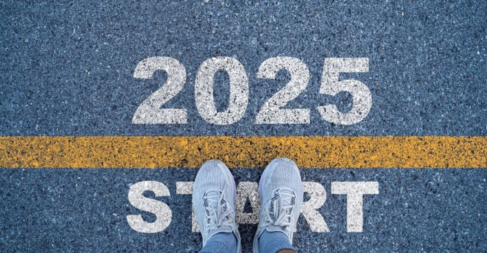 Schriftzug "2025 Start" und Sportschuhe auf einer Straße.