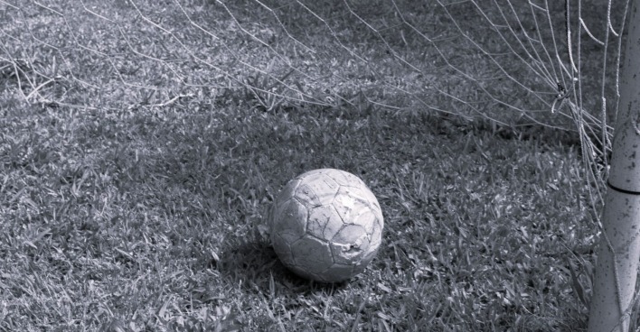 Fußball auf Platz im Tor liegend