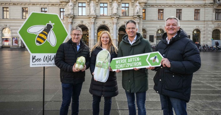 Mehrere Menschen mit Tafeln in der Hand stehen vor einem Rathaus