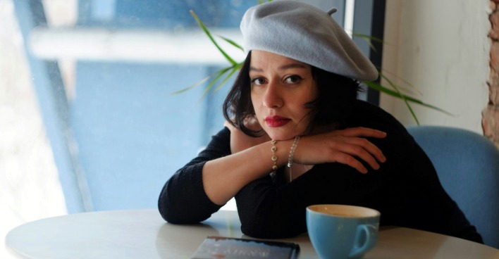 Eine Frau sitzt traurig mit einem Kaffee