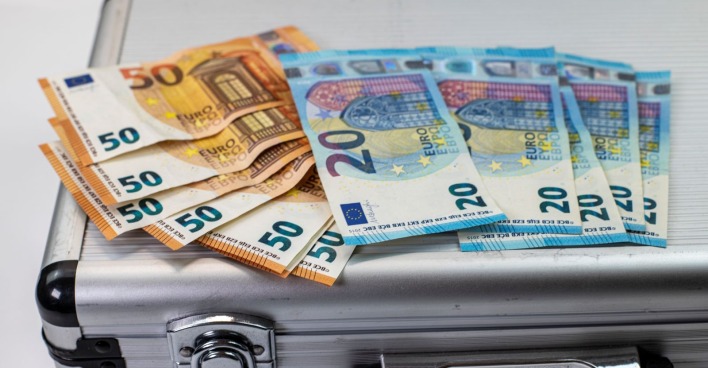 Geldscheine liegen auf Koffer