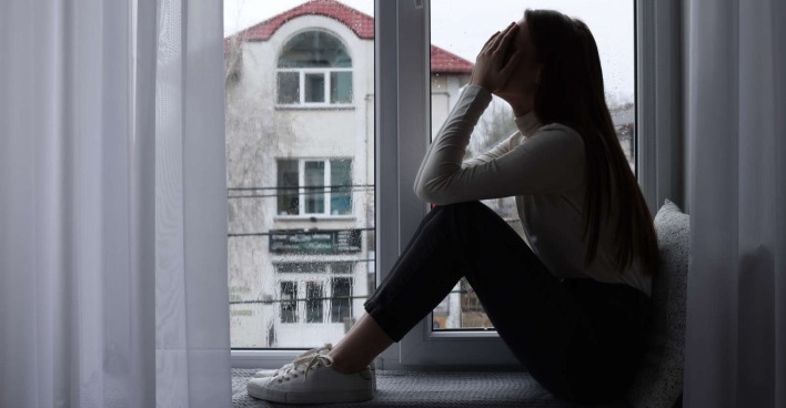 Eine verzweifelte Frau sitzt vor dem Fenster