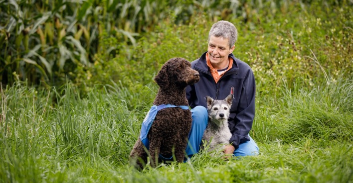 Gründerin Elisabeth Färbinger mit zwei ihrer Hund auf einer grünen Wiese.
