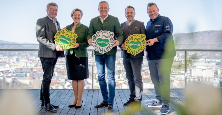 Organsiatoren und Unterstützer präsentieren das Steiermark-Frühlings-Logo auf einer Terrasse in Graz bei strahlendem Sonnenschein